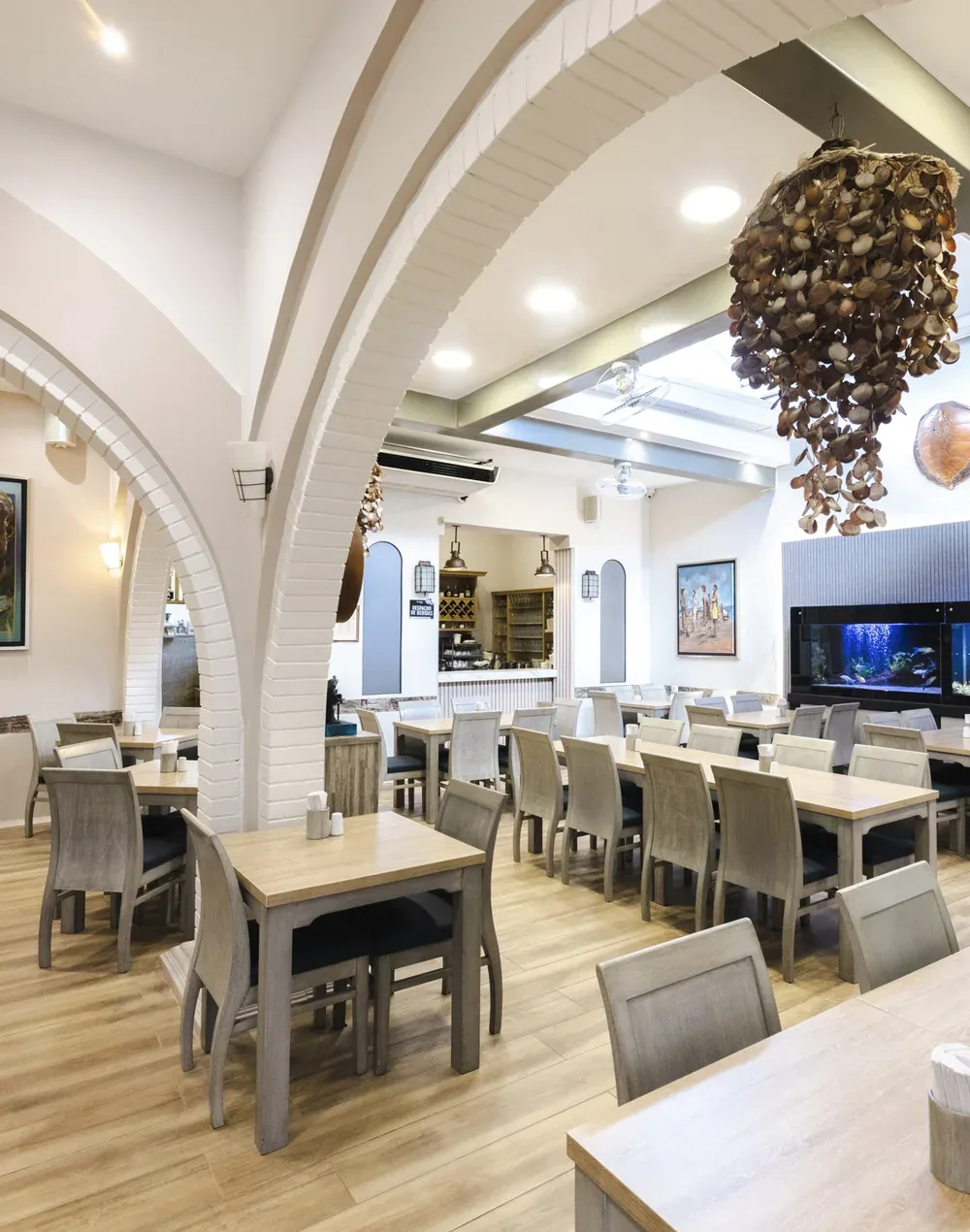 Salón con arcos de ladrillo blanco, acuario y lámpara de conchas en Pescocentro Búcaro, Bucaramanga